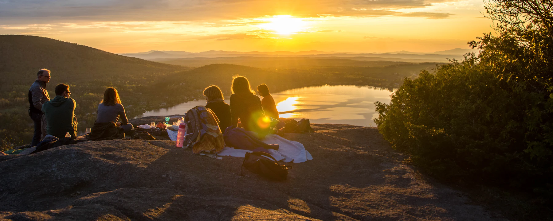 Friends watching the sunrise together over a lake